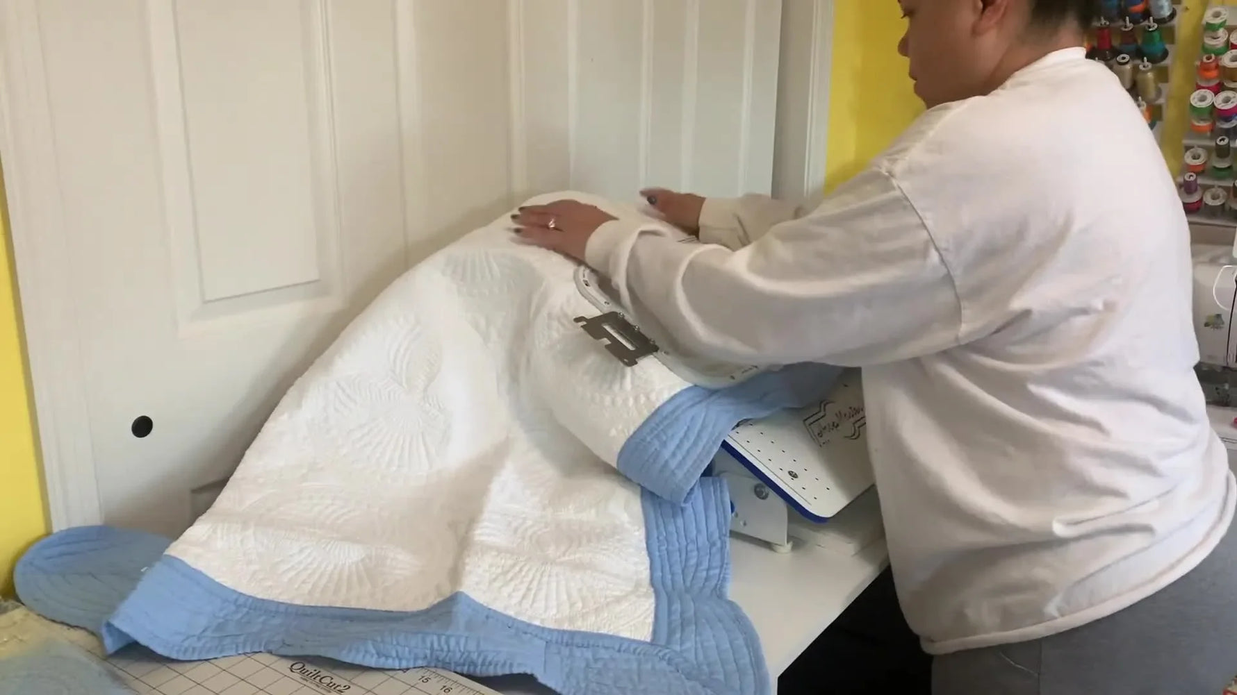 A top magnetic frame snaps down over a thick quilted baby blanket, holding the layers firmly for embroidery.